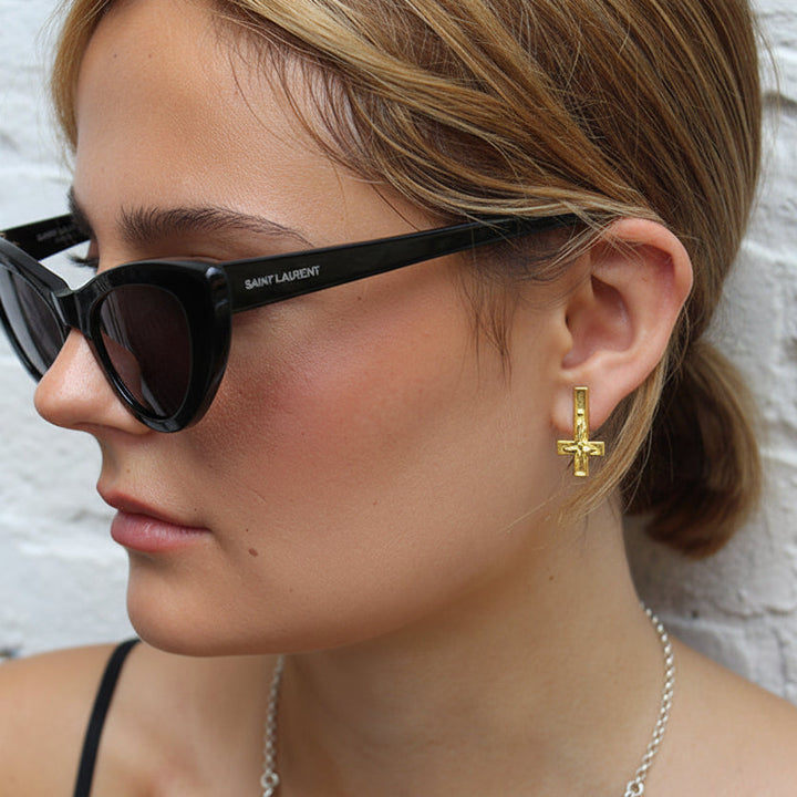 Close-up of a woman wearing black sunglasses and a silver necklace with a star pendant.