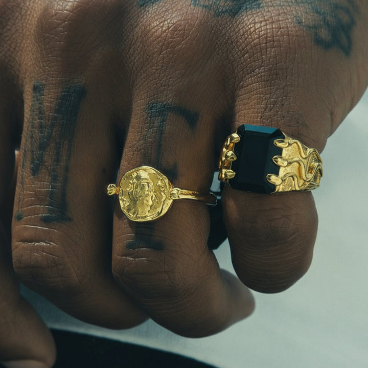 Hand with tattoos wearing two rings on a white background