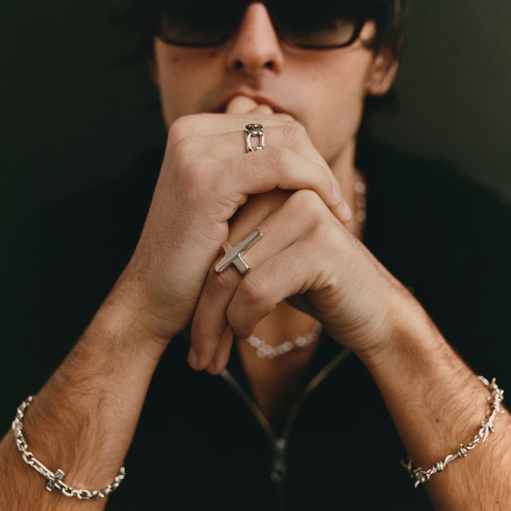 Person wearing multiple rings and bracelets with a dark background