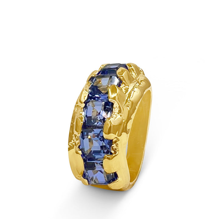 Gold ring with a blue gemstone on a white background