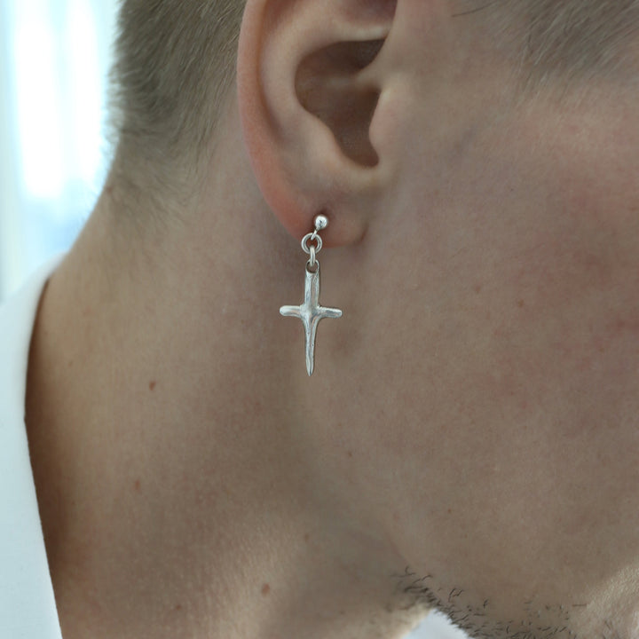 Close-up of a person wearing a silver cross earring.