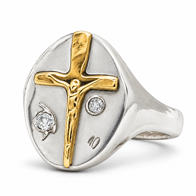 A two-tone silver and gold signet ring featuring a crucifix design with a small diamond accent, set against a clean white background.