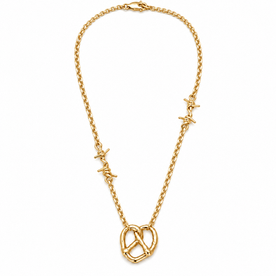 A gold chain necklace featuring 2 small barbed wire charms spaced along the chain and a large pretzel pendant at the center, shown on a plain white background.