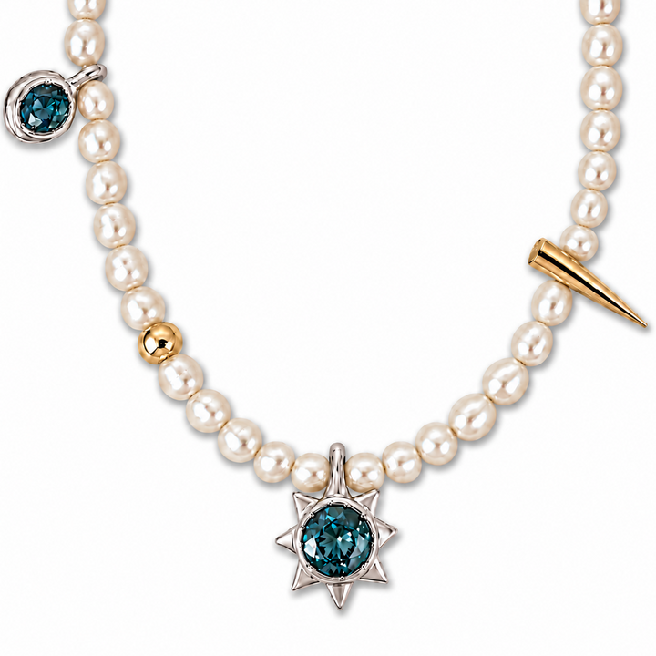 A pearl necklace featuring a central silver starburst pendant with a deep blue gemstone, a gold accent bead, a gold spike charm, and a smaller blue gemstone pendant on the side, set against a plain white background.