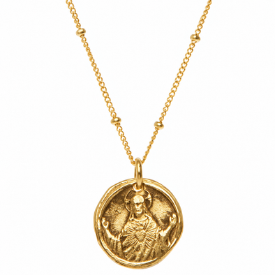 A gold necklace featuring a circular medallion pendant with an embossed figure, suspended from a delicate gold chain with small bead accents, set against a plain white background.