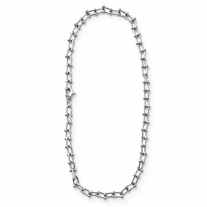 A silver-toned metal link chain necklace arranged in an oval shape on a plain white background.