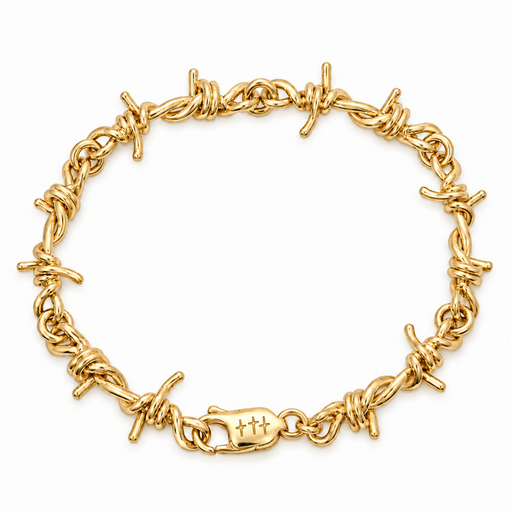 A yellow gold barbed wire bracelet with a matching lobster clasp engraved with three crosses, displayed on a clean white background.