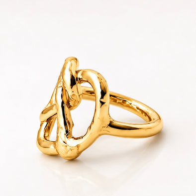 A polished gold ring with an organic, intertwined knot-like design, photographed on a clean white background.