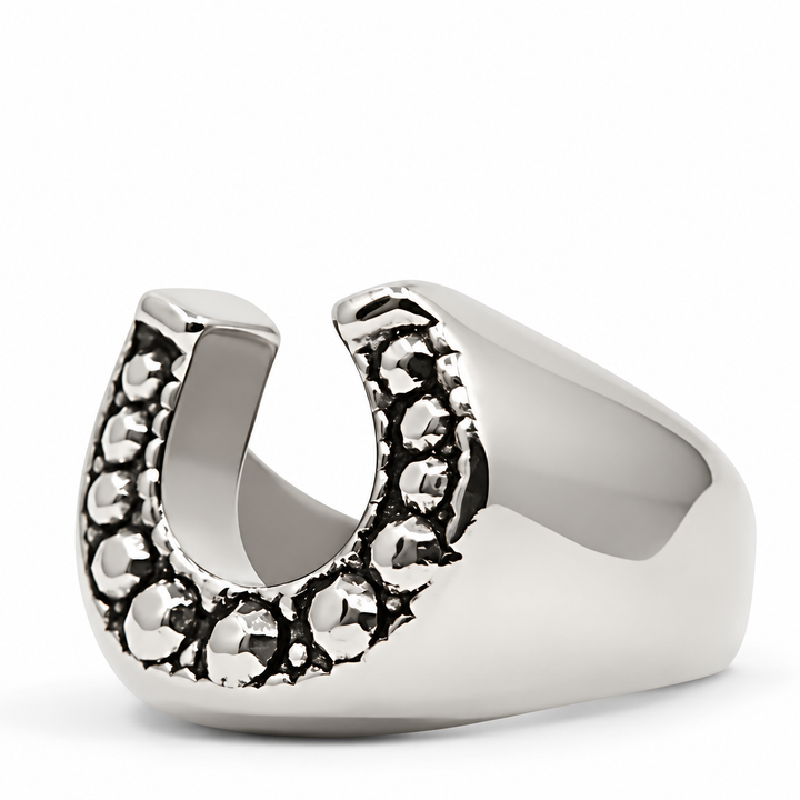 A polished silver horseshoe-shaped ring with textured, oxidized detailing along the outer edges, shown on a clean white background.