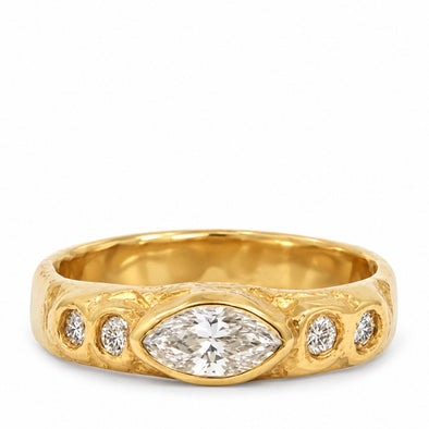 A yellow gold ring featuring a marquise-cut diamond center stone and three smaller round diamonds set in a textured, organic-shaped band, shown on a plain white background.
