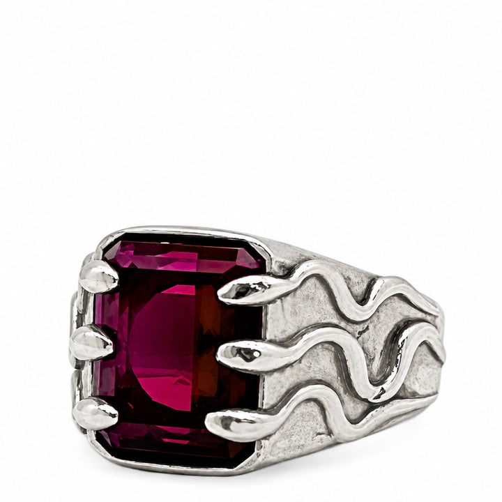 A silver-toned men's signet ring featuring a large, rectangular, faceted deep magenta-purple gemstone, set against a plain white background.