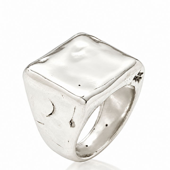 A sterling silver signet ring with a heavily textured, organic square face and a polished band, shown on a clean white background with a soft reflection.