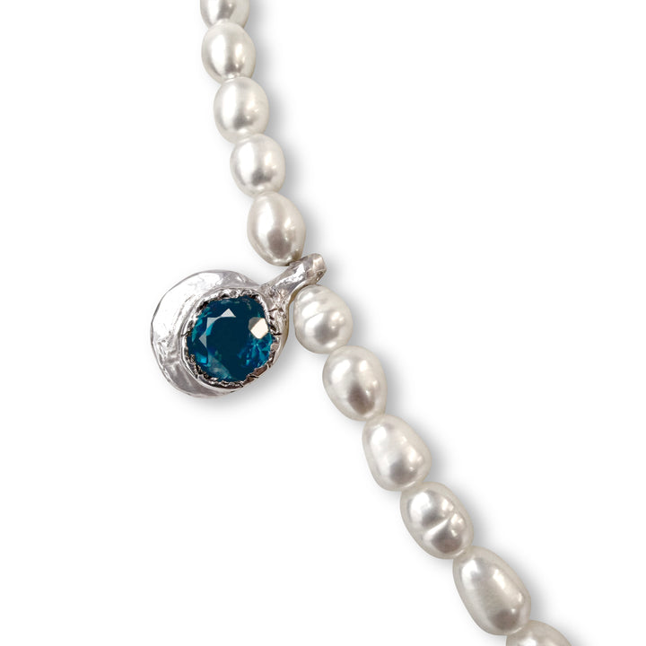Pearl necklace with a blue gemstone pendant on a white background