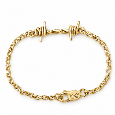 A gold chain bracelet with twisted barbed wire details at the top and a lobster clasp engraved with 'BRITT BOLTON', shown on a plain white background.
