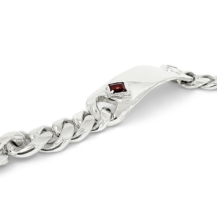 Silver chain bracelet with a red gemstone on a white background
