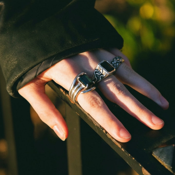 Hand with multiple rings on a blurred natural background