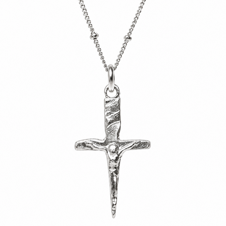 A silver crucifix pendant necklace featuring a textured dagger hilt and a detailed figure of Jesus Christ, suspended from a delicate silver chain against a plain white background.