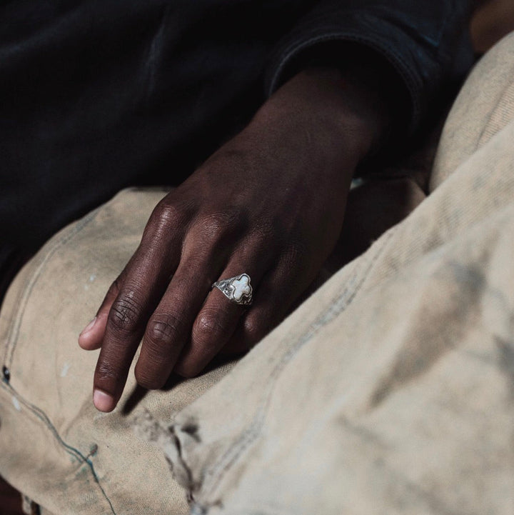 Hand wearing a ring on a worn-out leather surface