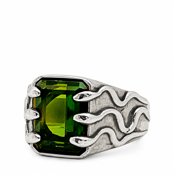 A silver ring featuring a large, faceted green rectangular gemstone with a wavy, flame-like textured band, shown on a plain white background.