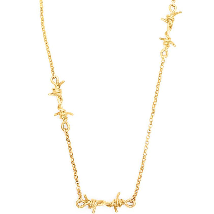 A gold necklace featuring a chain link design with three barbed wire link pendants asymmetrically placed along the chain.