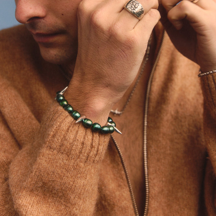 Person wearing a brown sweater with jewelry against a blue background