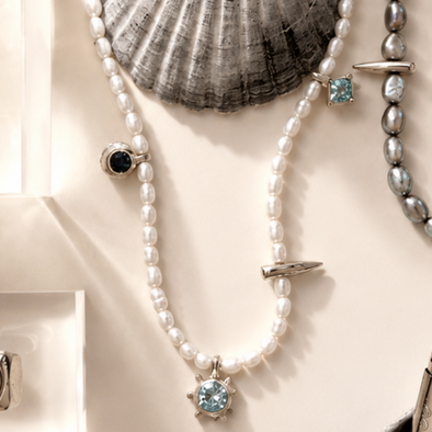 Jewelry including a bracelet, necklace, and rings displayed on a neutral background with shells.