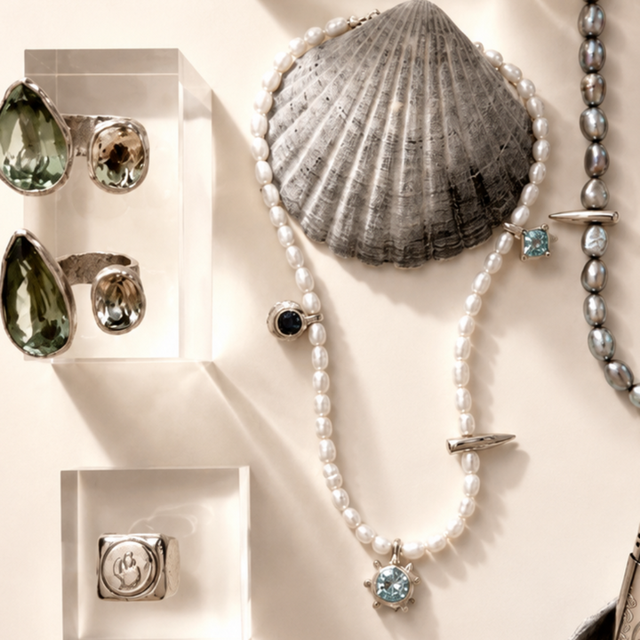 Jewelry including a bracelet, necklace, and rings displayed on a neutral background with shells.