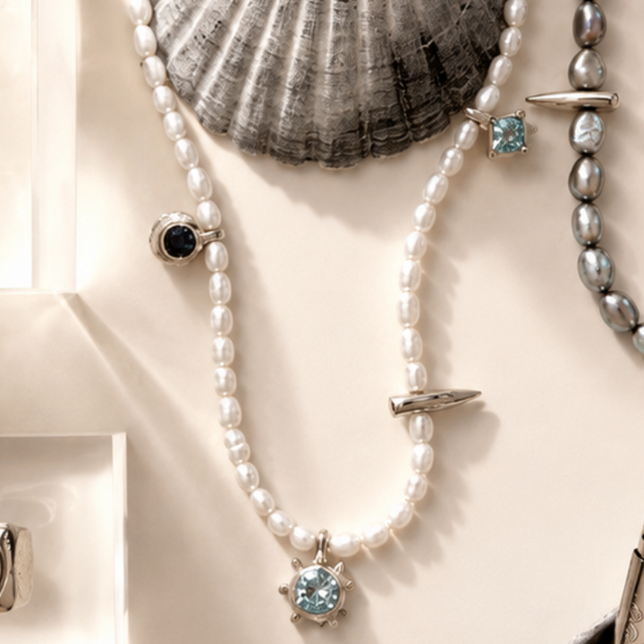 Jewelry including a bracelet, necklace, and rings displayed on a neutral background with shells.