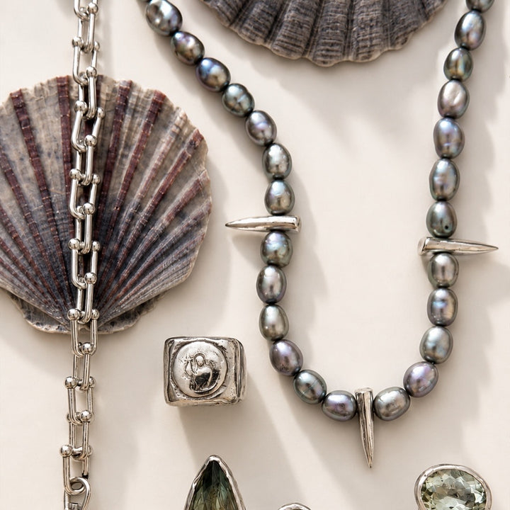 Jewelry set with pearls, silver chain, and shell elements on a light background
