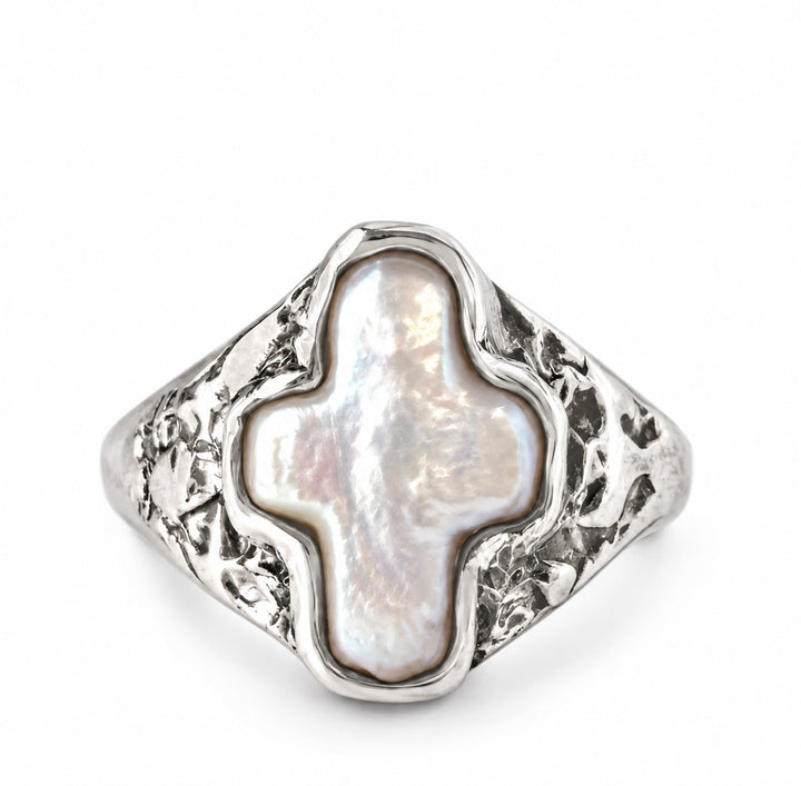 A silver signet ring featuring a large, irregularly shaped white mother-of-pearl cross-shaped centerpiece, set against a clean white background.