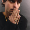 Man wearing a black sweater and gold ring with a blurred background