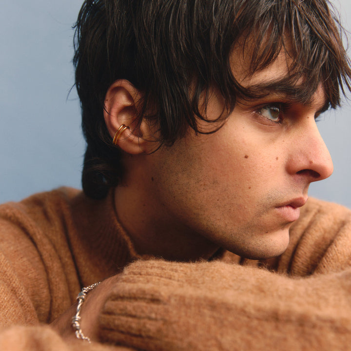 Man wearing a brown sweater against a light blue background
