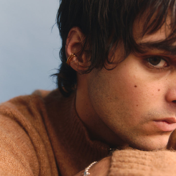 Man wearing a brown sweater with a neutral background
