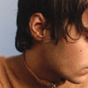 Close-up of a person wearing an earring with a neutral background