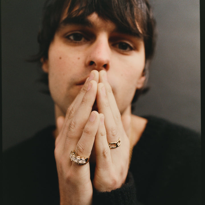 Man with rings on his fingers against a dark background