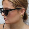 Close-up of a woman wearing black sunglasses and a silver necklace with a star pendant.