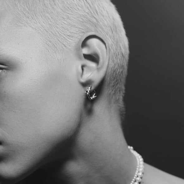 Close-up of a person wearing a pearl necklace and earring with a blurred background