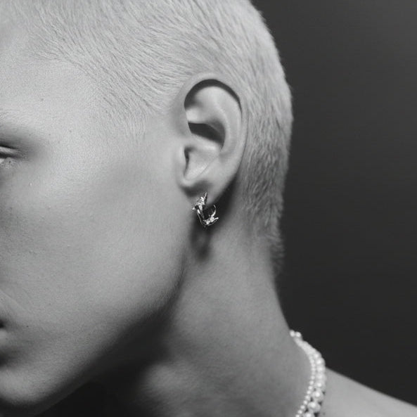 Close-up of a person wearing a pearl necklace and earring with a blurred background