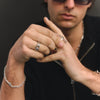 Man wearing sunglasses and multiple rings on a dark background