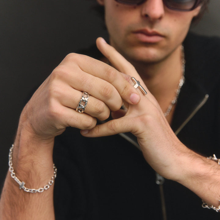 Man wearing sunglasses and multiple rings on a dark background