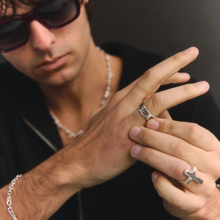 Man wearing multiple rings and a bracelet on a dark background