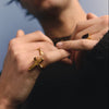 Man wearing a gold cross ring against a blurred background