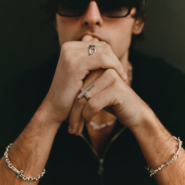 Person wearing multiple rings and bracelets with a dark background