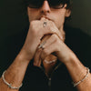 Person wearing multiple rings and bracelets with a dark background
