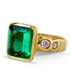 Gold ring with a large green gemstone and smaller diamonds on a white background