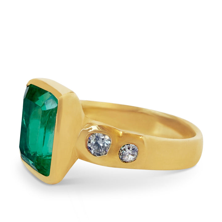 Gold ring with a green gemstone and two smaller diamonds on a white background