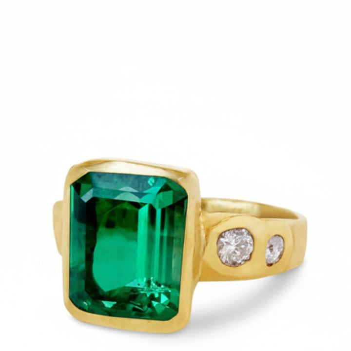 Gold ring with a large green gemstone and smaller diamonds on a white background