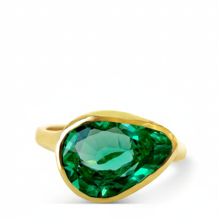 Gold ring with a green gemstone on a white background