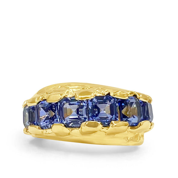 Gold ring with blue gemstones on a white background