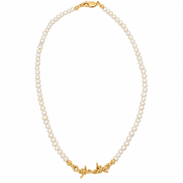 A delicate necklace made of small white pearls with gold-toned metal accents, including a lobster clasp and a decorative barbed wire style charm, shown on a plain white background.